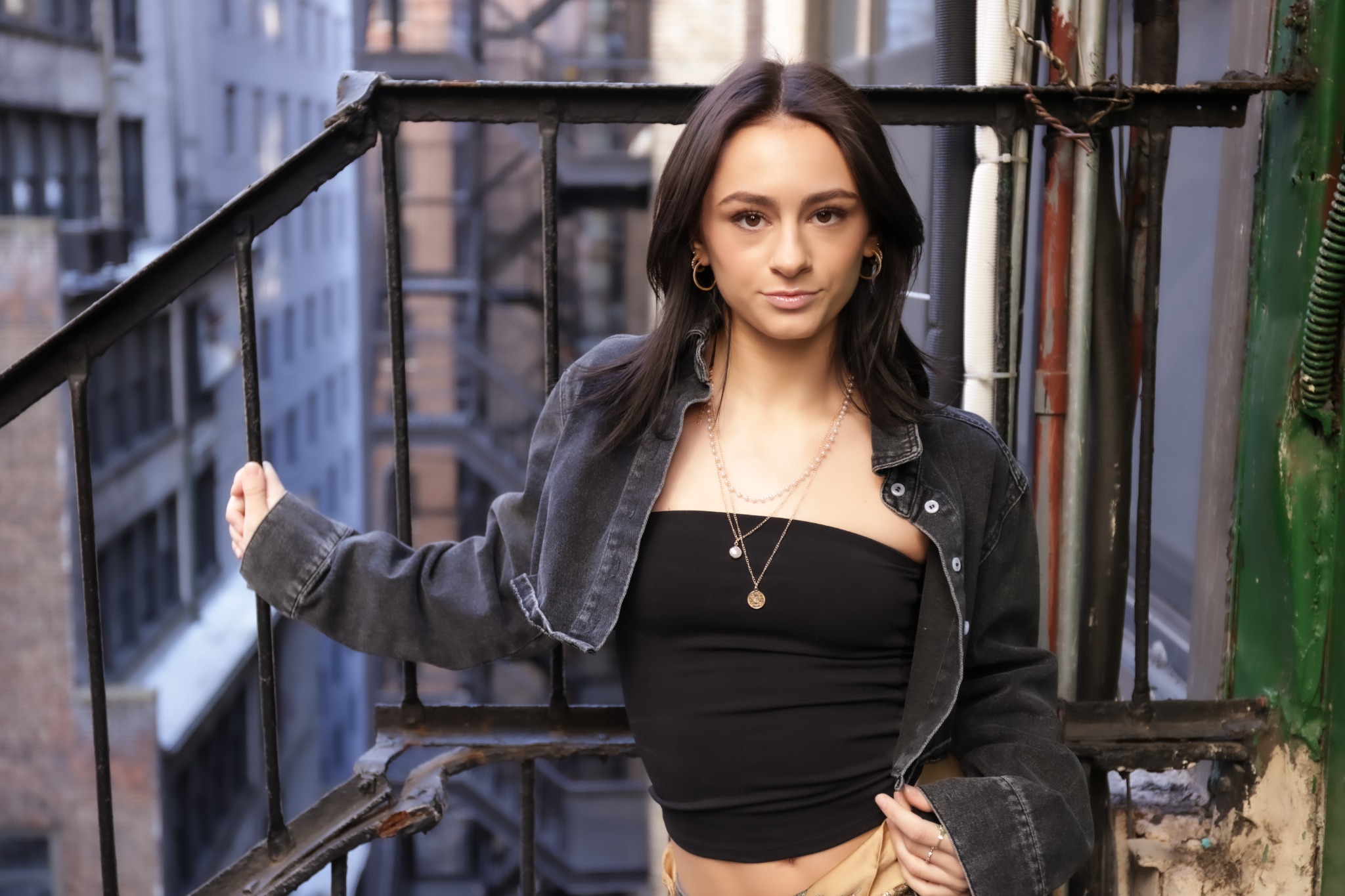 Ava Ziegler in a black streetwear look on a city fire escape